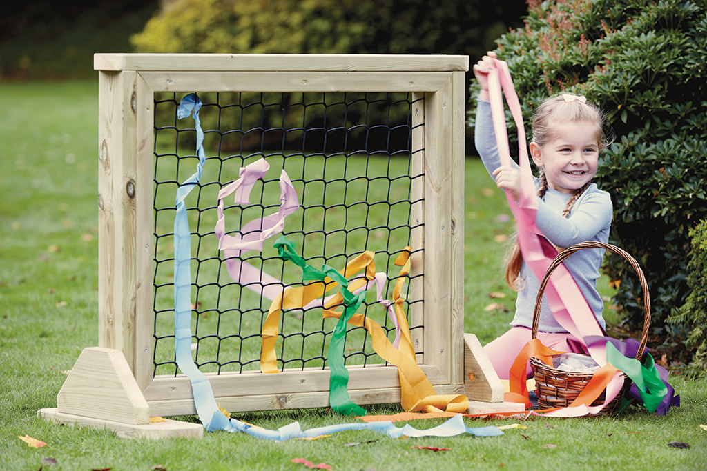 rear project image, playground frame, colorful streamers, child with ribbons, outdoor hobby crafts, Kindertagesdekoration, Röhrchenbänder, Korb mit Bändern, Spiel im Freien, Holzkäfig
