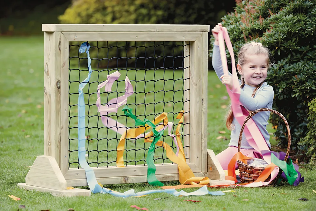 rear project image, playground frame, colorful streamers, child with ribbons, outdoor hobby crafts, Kindertagesdekoration, Röhrchenbänder, Korb mit Bändern, Spiel im Freien, Holzkäfig