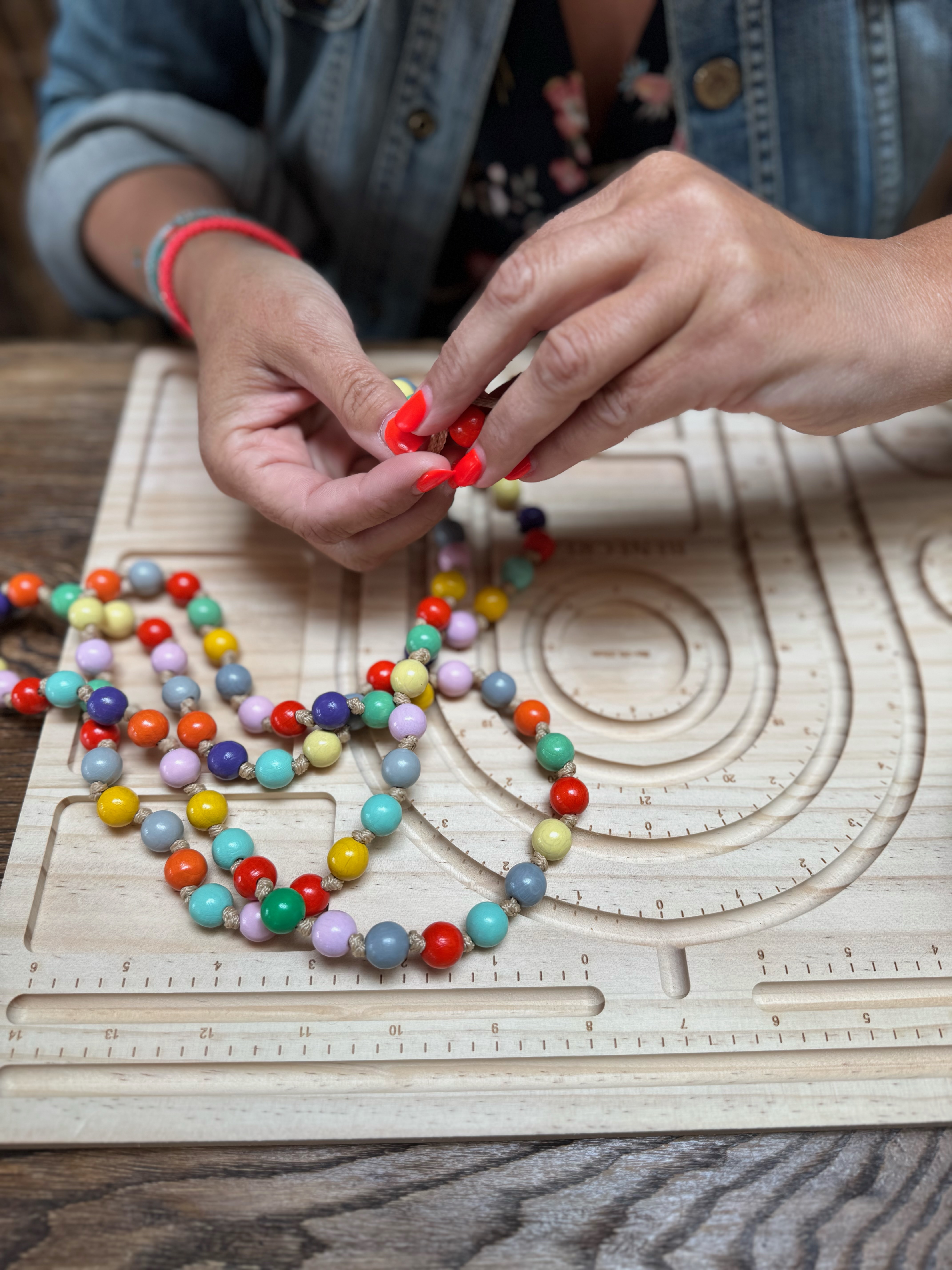 Marion Fischer bastelt an einem Perlenbrett eine bunte Handykette aus Holzperlen mit einer speziellen Knotenrechnik Marion Fischer bastelt an einem Perlenbrett eine bunte Handykette aus Holzperlen mit einer speziellen Knotenrechnik